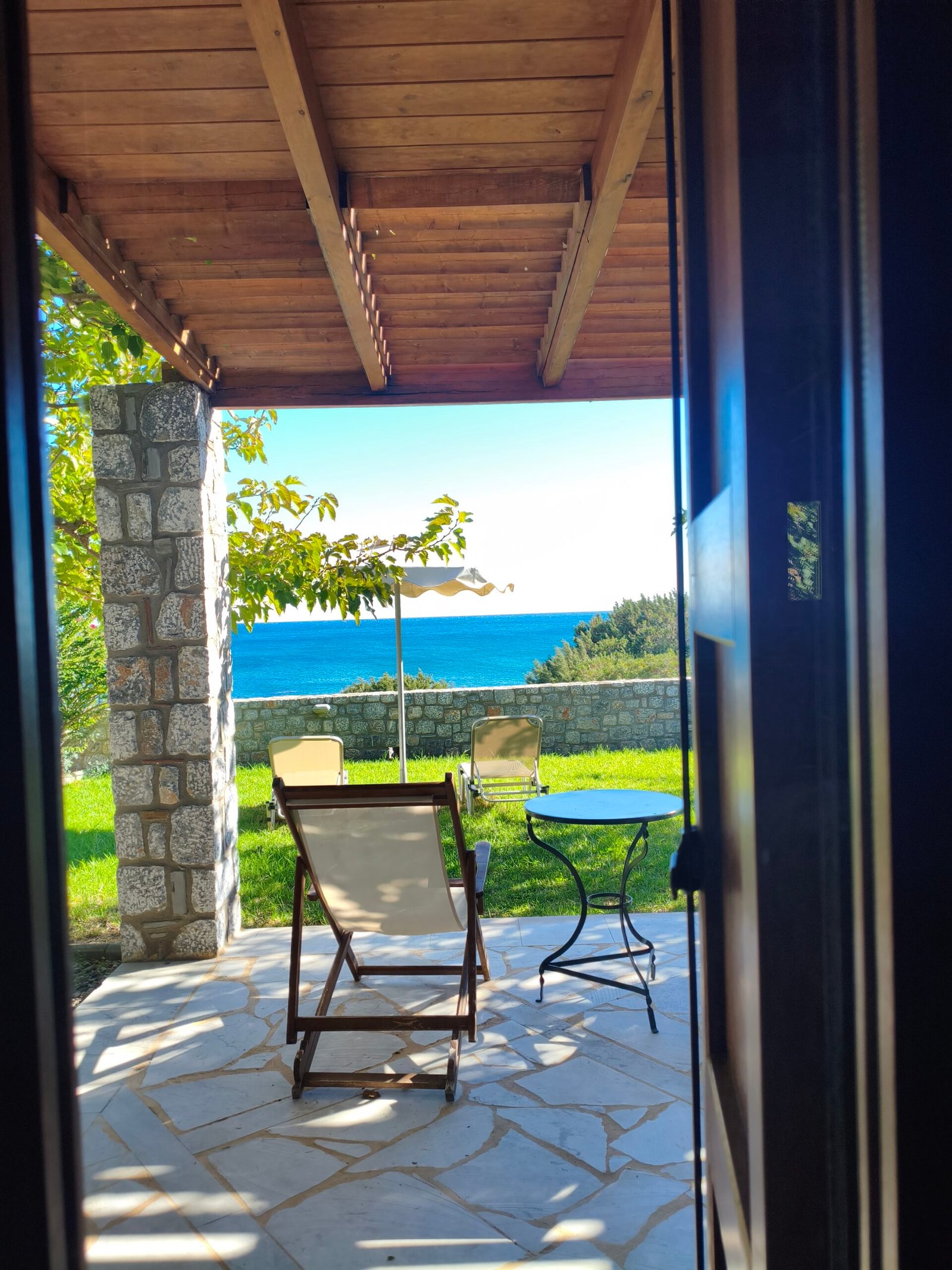 View from the living room toward the outdoor seating area with sea view at Alisahni Villas in Kiotari, Rhodes.